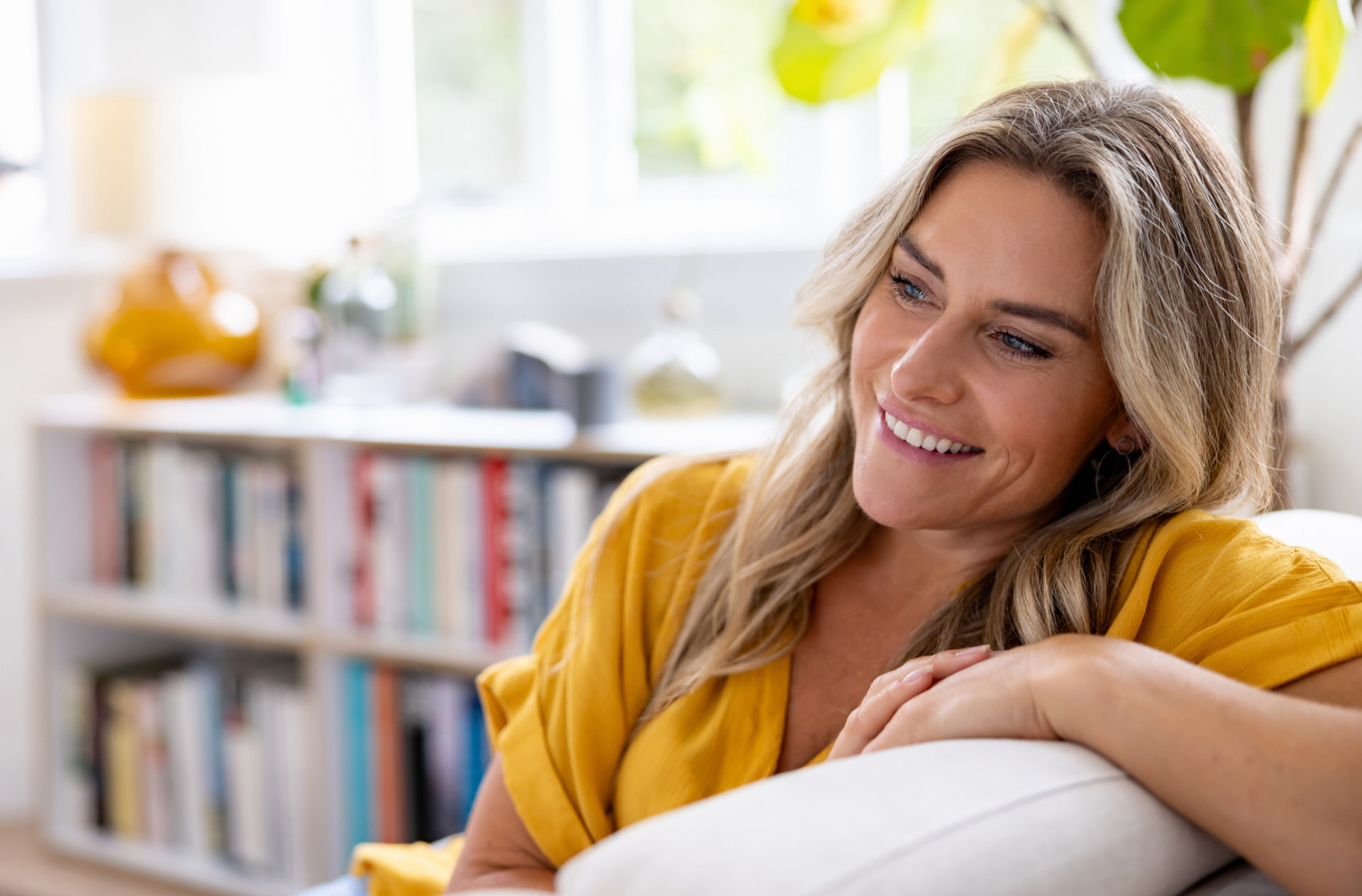 A woman resting comfortably on her couch at home in warm natural light