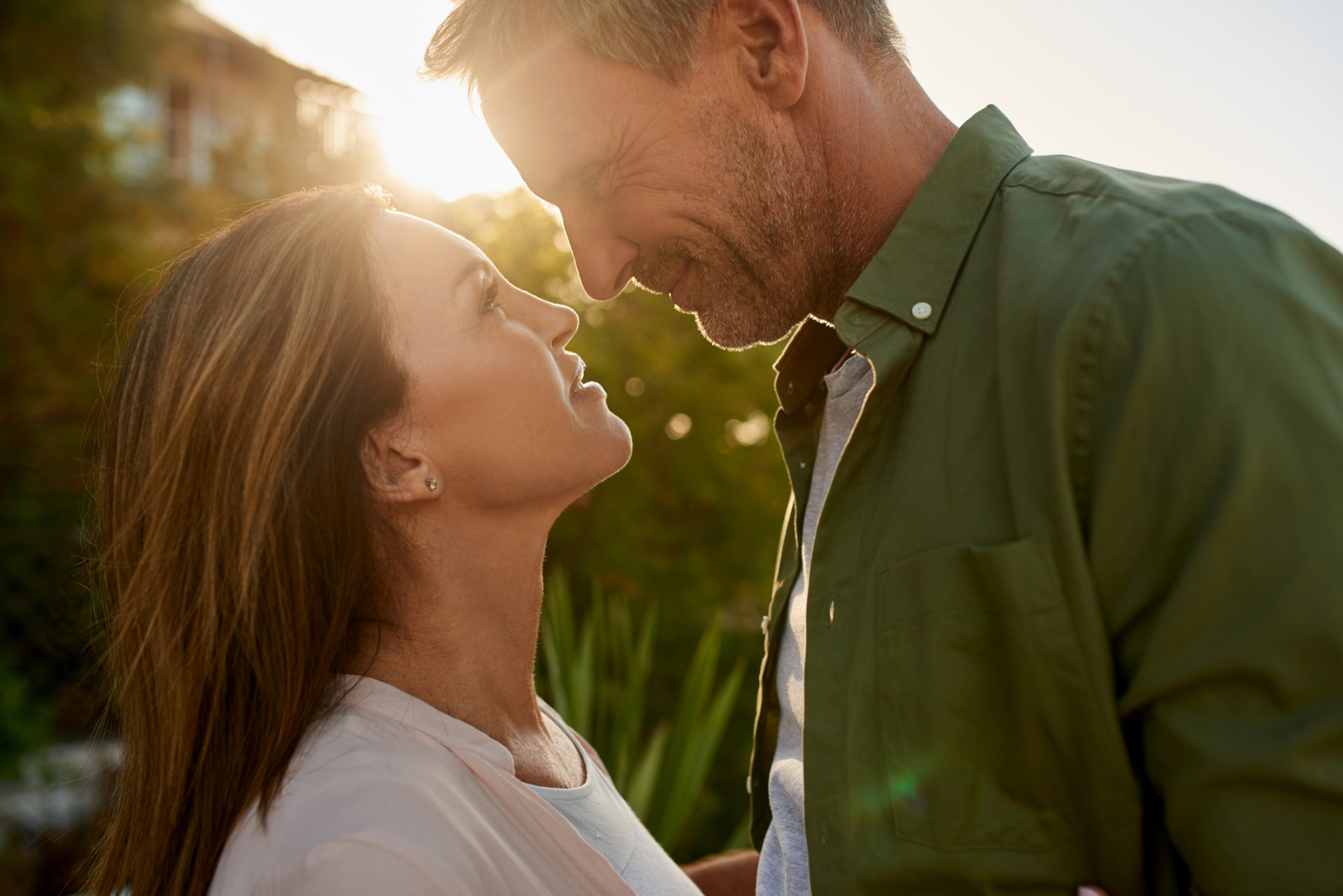 Midlife couple outdoors in warm golden light, smiling at each other