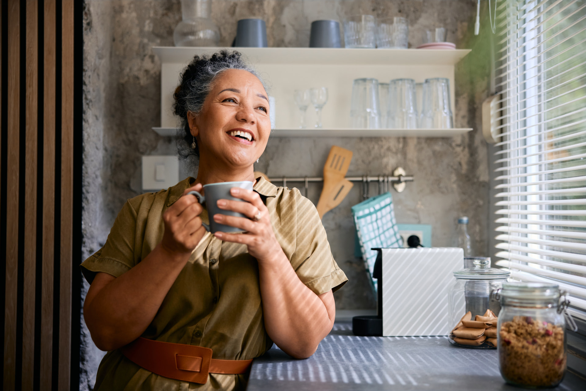 Woman smiling with a cup of coffee in her kitchen