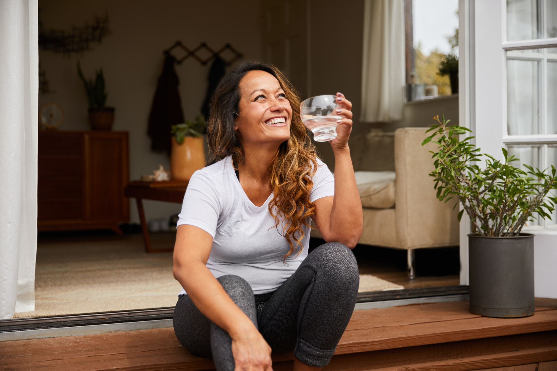 Smiling midlife woman relaxing at home with a glass of water