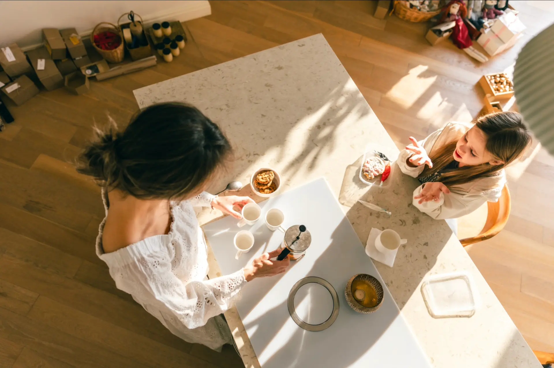 Two people talking over coffee at a sunlit kitchen table