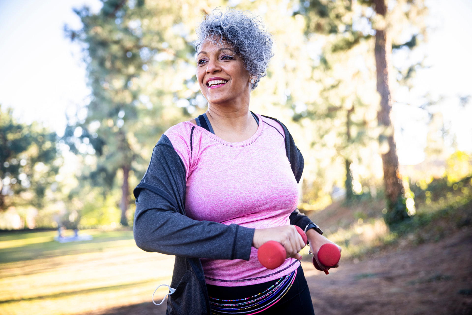 Woman exercising with light dumbbells outdoors in a park