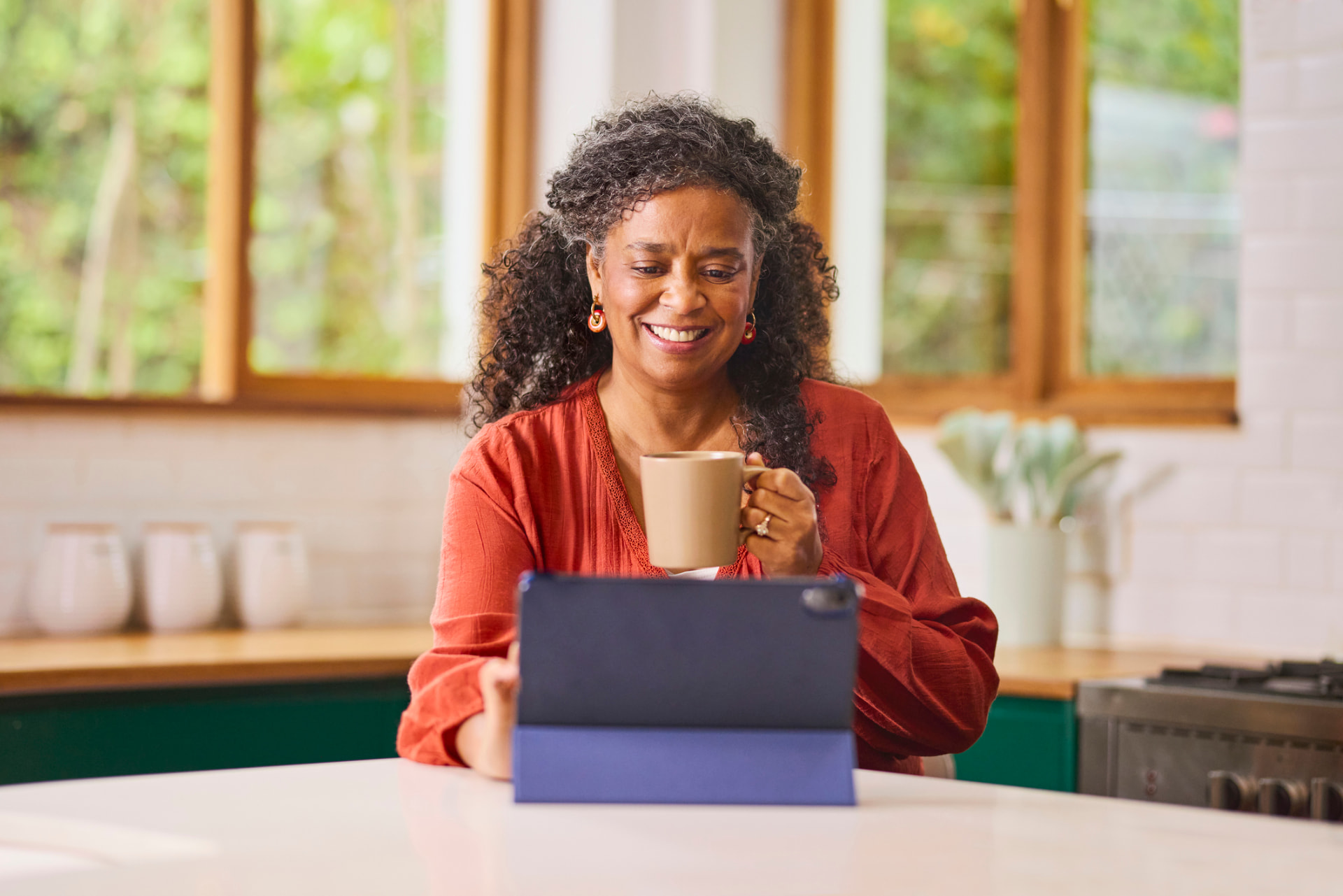 Woman on a telehealth visit at her kitchen counter with a cup of coffee