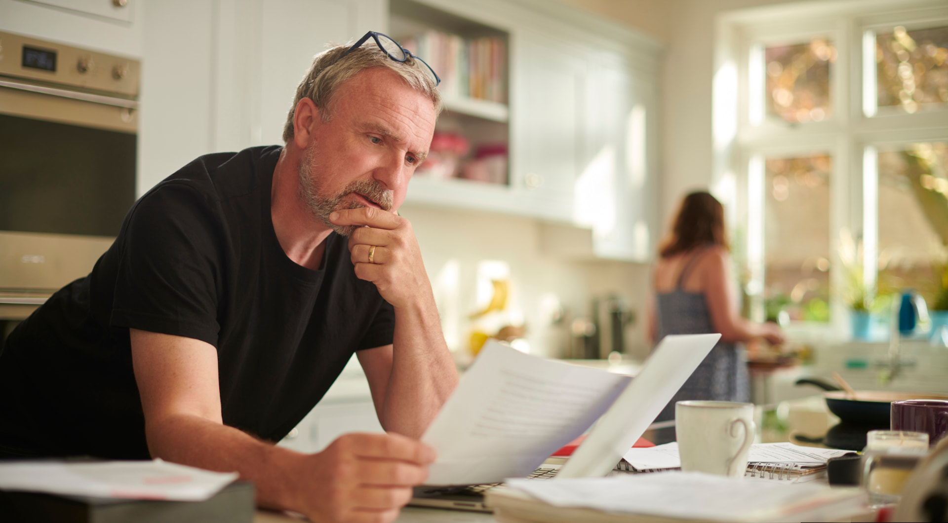 A man reading printed lab results at his kitchen counter