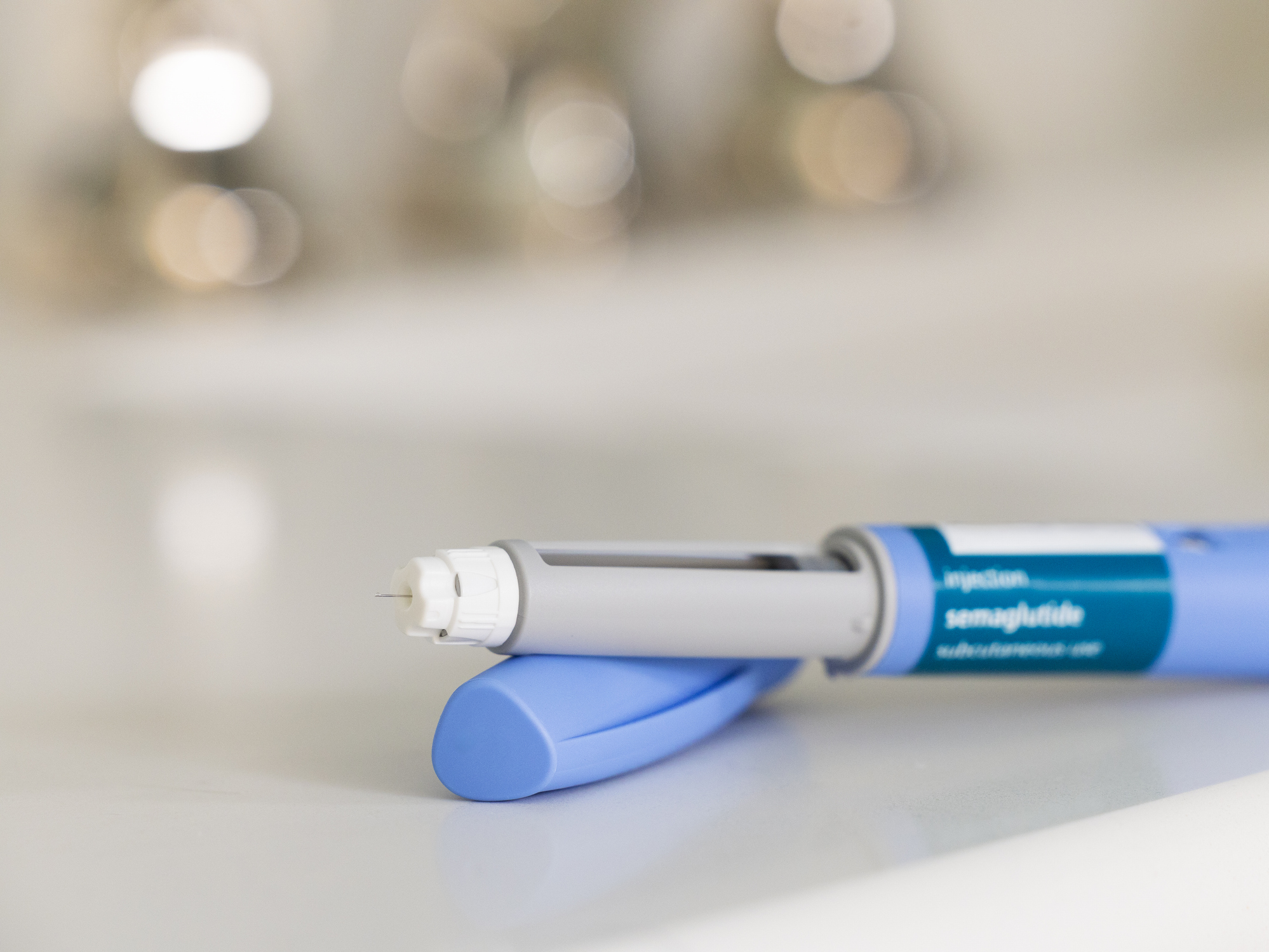 Close-up of a brand-name semaglutide injection pen with the needle attached, resting on a counter